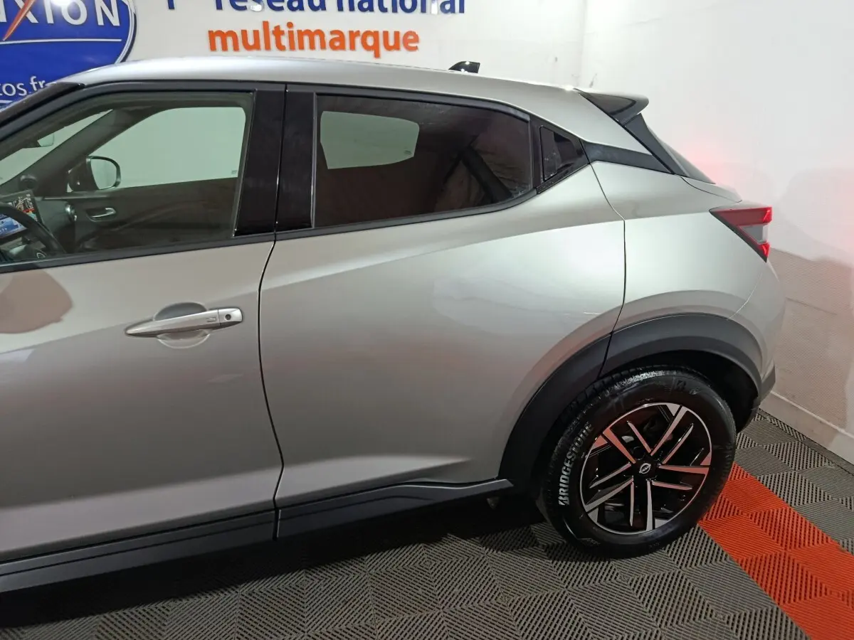 Vue latérale droite du Nissan Juke gris foncé 2025, mettant en valeur la ligne de caisse et la jante noire à détails argentés.