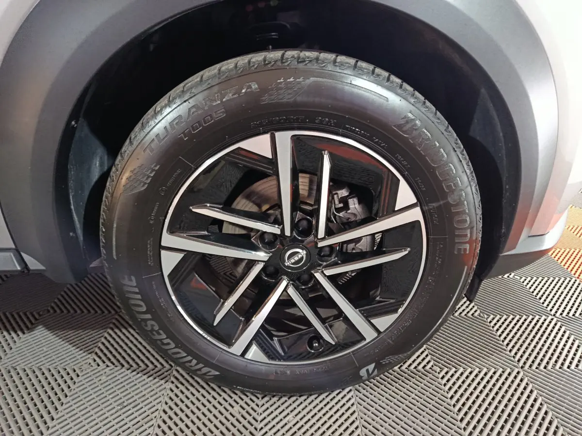 Gros plan sur la roue avant droite du Nissan Juke gris foncé, jante alliage noir et argent avec pneu Bridgestone.