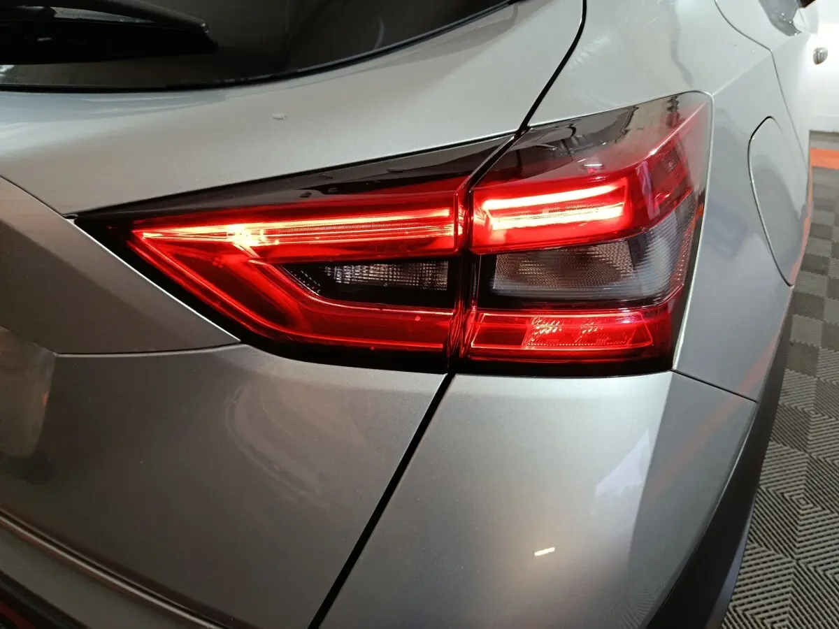 Gros plan sur le feu arrière droit rouge vif d’un Nissan Juke gris foncé 2025, soulignant ses lignes modernes.