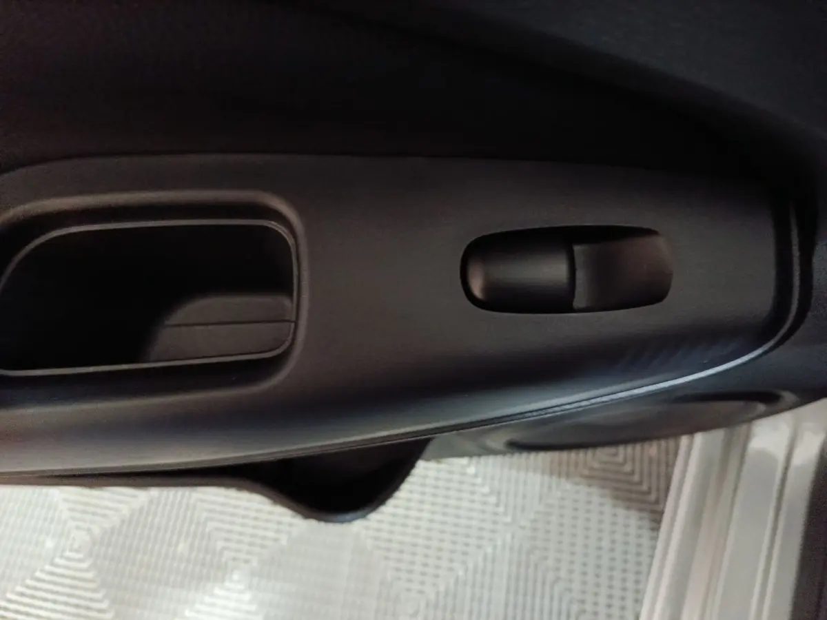 Gros plan sur la poignée intérieure noire de la porte côté conducteur du Nissan Juke gris foncé 2025.