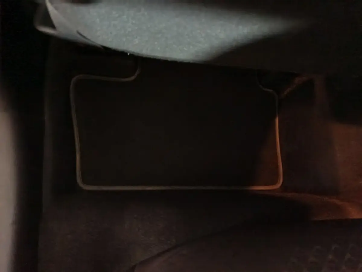 Gros plan sur le tapis de sol noir à bordures claires dans l'habitacle du Nissan Juke gris foncé 2025.