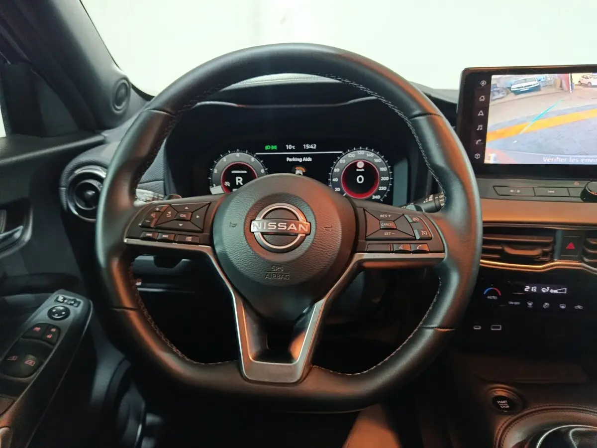 Vue intérieure centrée sur le volant noir du Nissan Juke 2025 avec tableau de bord numérique et écran tactile latéral.