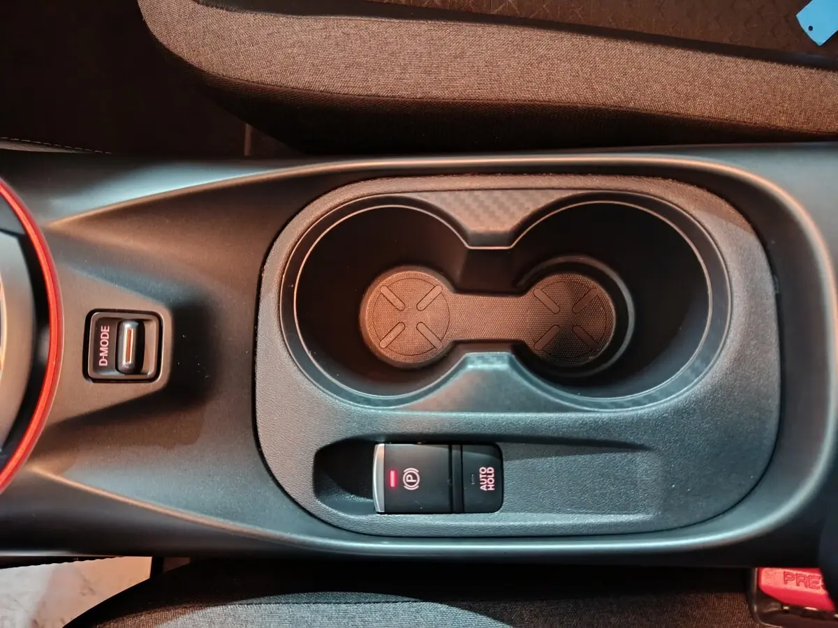 Vue plongeante sur la console centrale du Nissan Juke gris foncé, avec porte-gobelets et frein à main électrique.