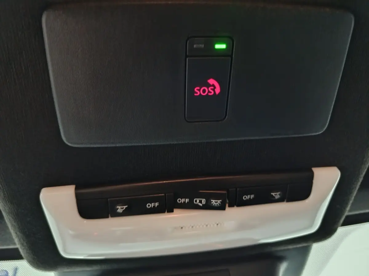 Gros plan sur le plafonnier noir avec bouton SOS illuminé en rouge dans un Nissan Juke gris foncé 2025.