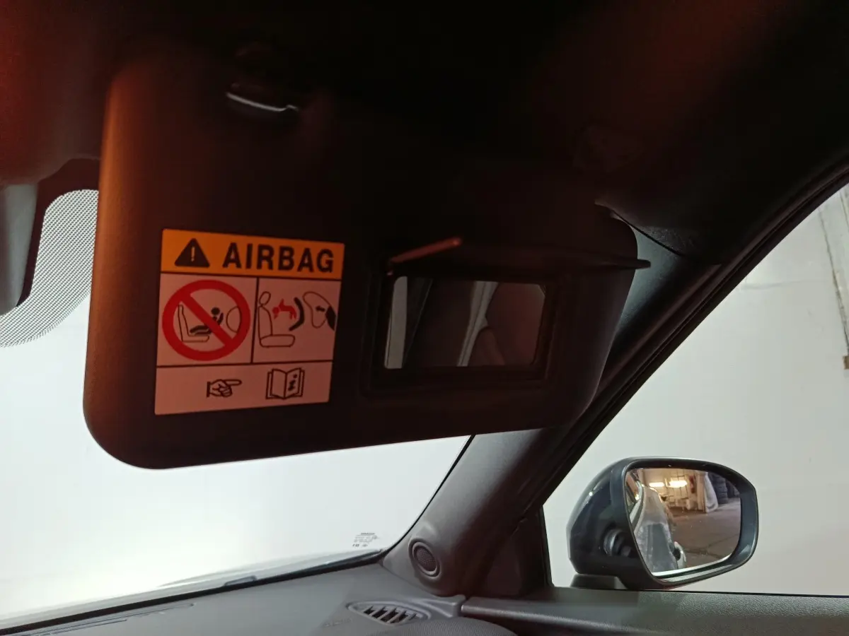 Intérieur Nissan Juke 2025, vue côté conducteur sur pare-soleil avec miroir et rétroviseur extérieur noir.