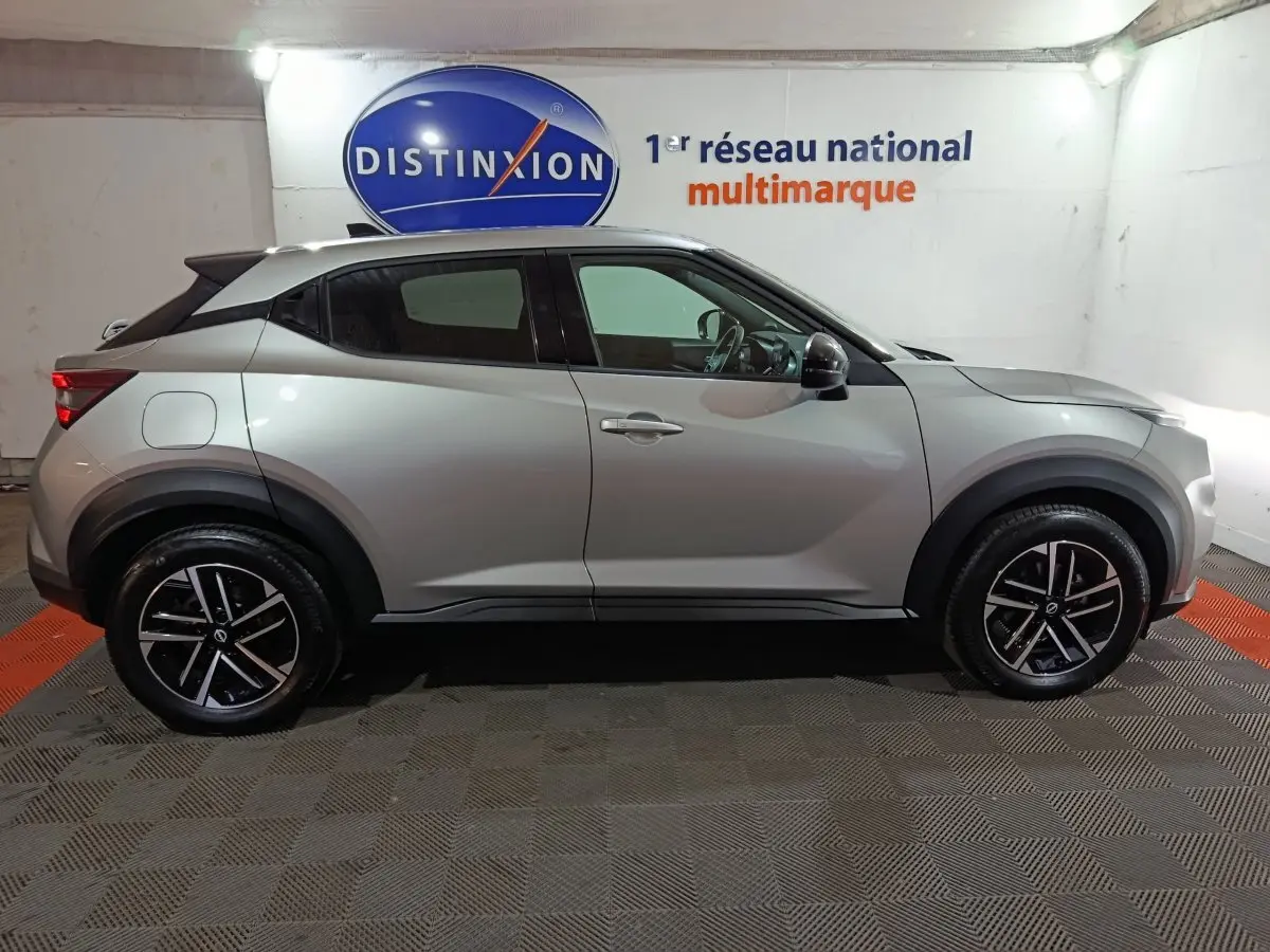 Vue de profil côté gauche d'un Nissan Juke gris foncé 2025 avec jantes noires et détails noirs contrastants.