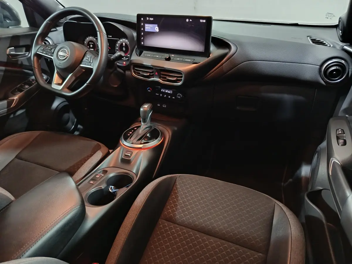 Vue intérieure côté conducteur du Nissan Juke 2025 gris foncé, avec tableau de bord numérique et écran tactile central.