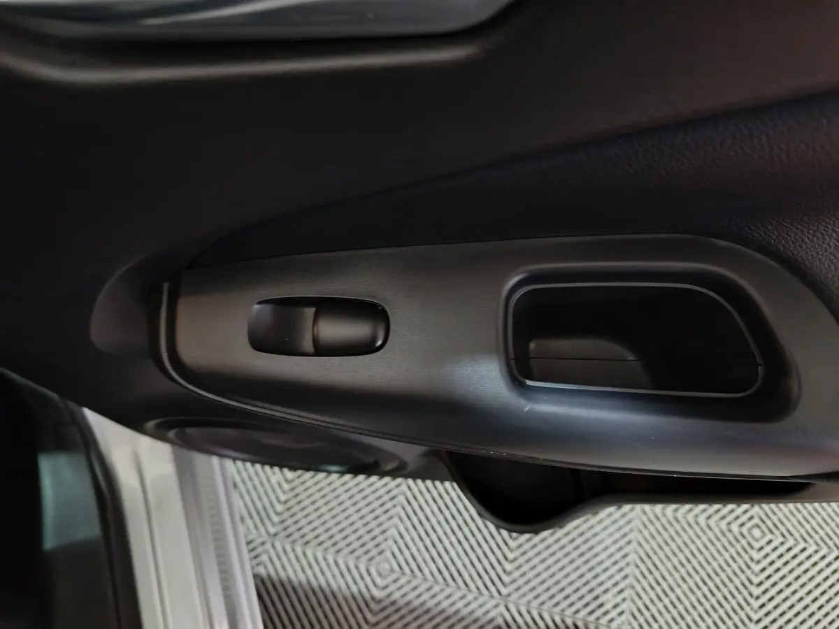 Détail de la poignée intérieure de porte côté conducteur du Nissan Juke gris foncé, finition 2025.