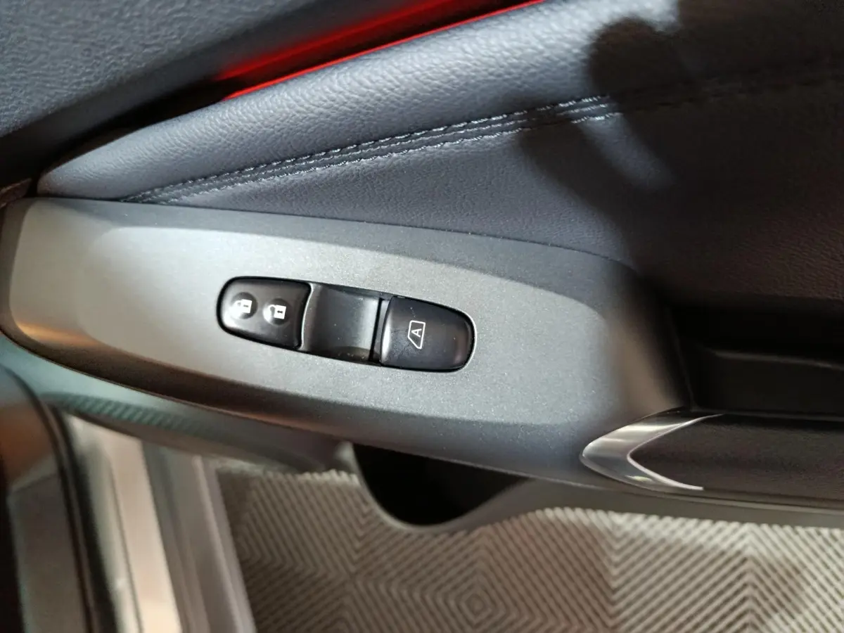 Détail des commandes de verrouillage centralisé sur la portière côté conducteur du Nissan Juke gris foncé 2025.