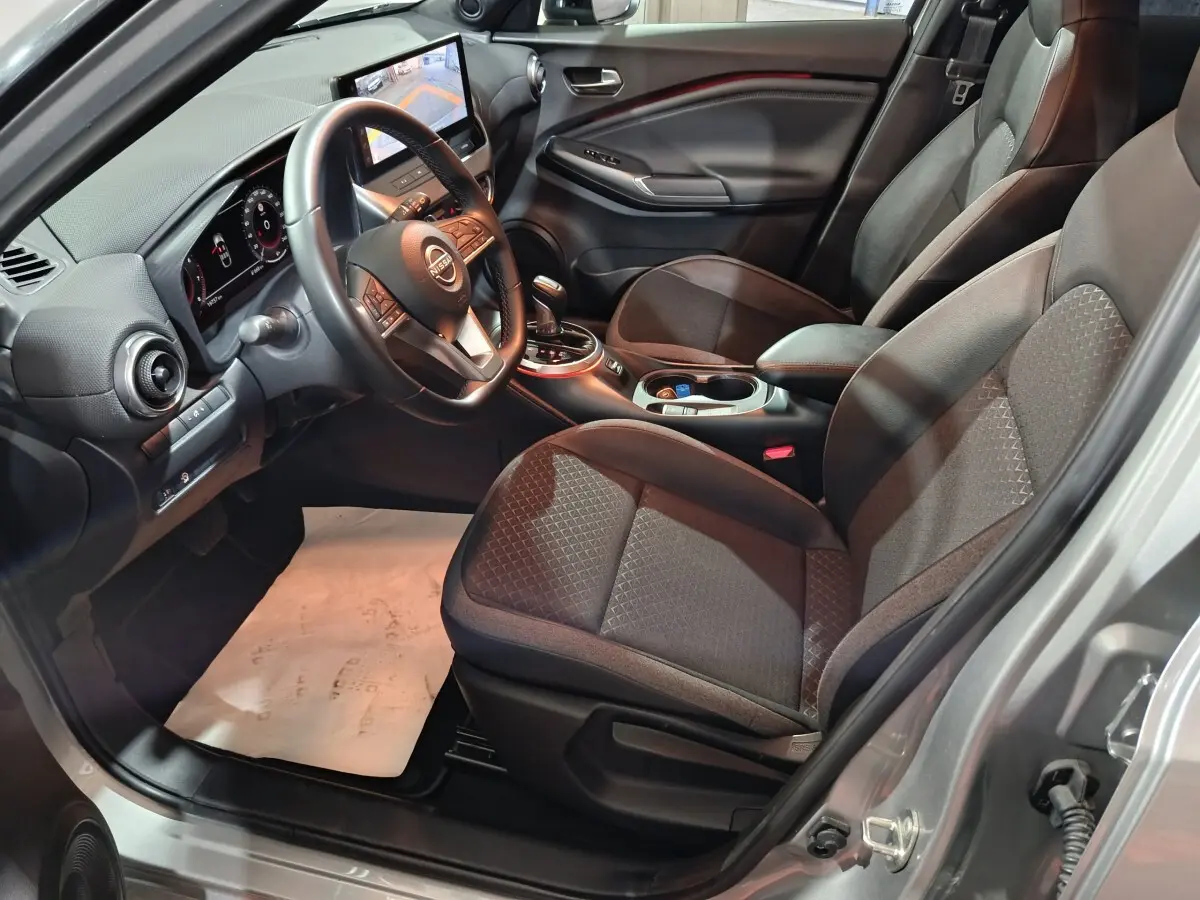 Intérieur avant droit du Nissan Juke gris foncé 2025, avec tableau de bord numérique et écran tactile central.