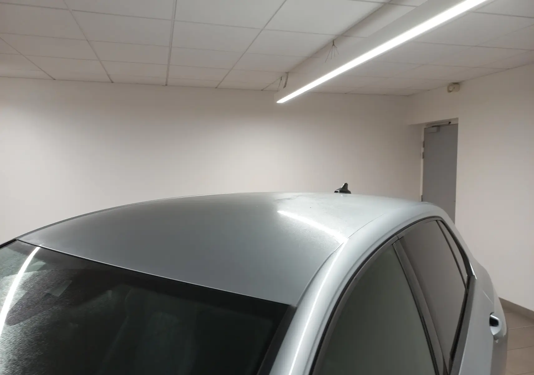 Vue partielle en plongée montrant le toit et les vitres teintées d'une Volkswagen Golf 1.5 eTSI argent dolomite en intérieur.