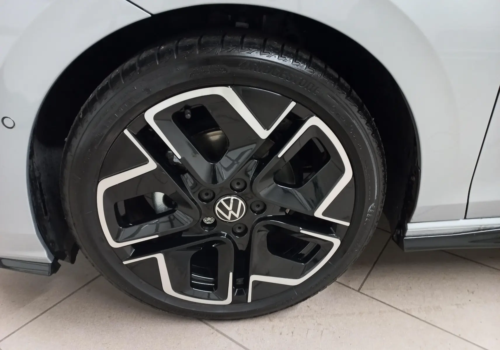 Gros plan sur la roue avant gauche de la Volkswagen Golf 1.5 eTSI R-Line argent dolomite avec jante noire et argentée.