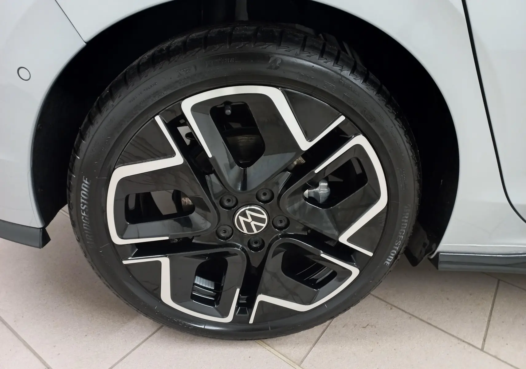 Gros plan sur la roue avant gauche de la Volkswagen Golf 1.5 eTSI 150 DSG7 R-Line argent dolomite avec jante noire et argentée.