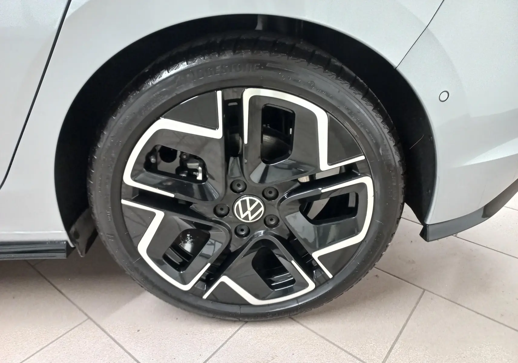Gros plan sur la roue avant gauche d’une Volkswagen Golf 1.5 eTSI 150 R-Line argent dolomite avec jante noire et détails argentés.