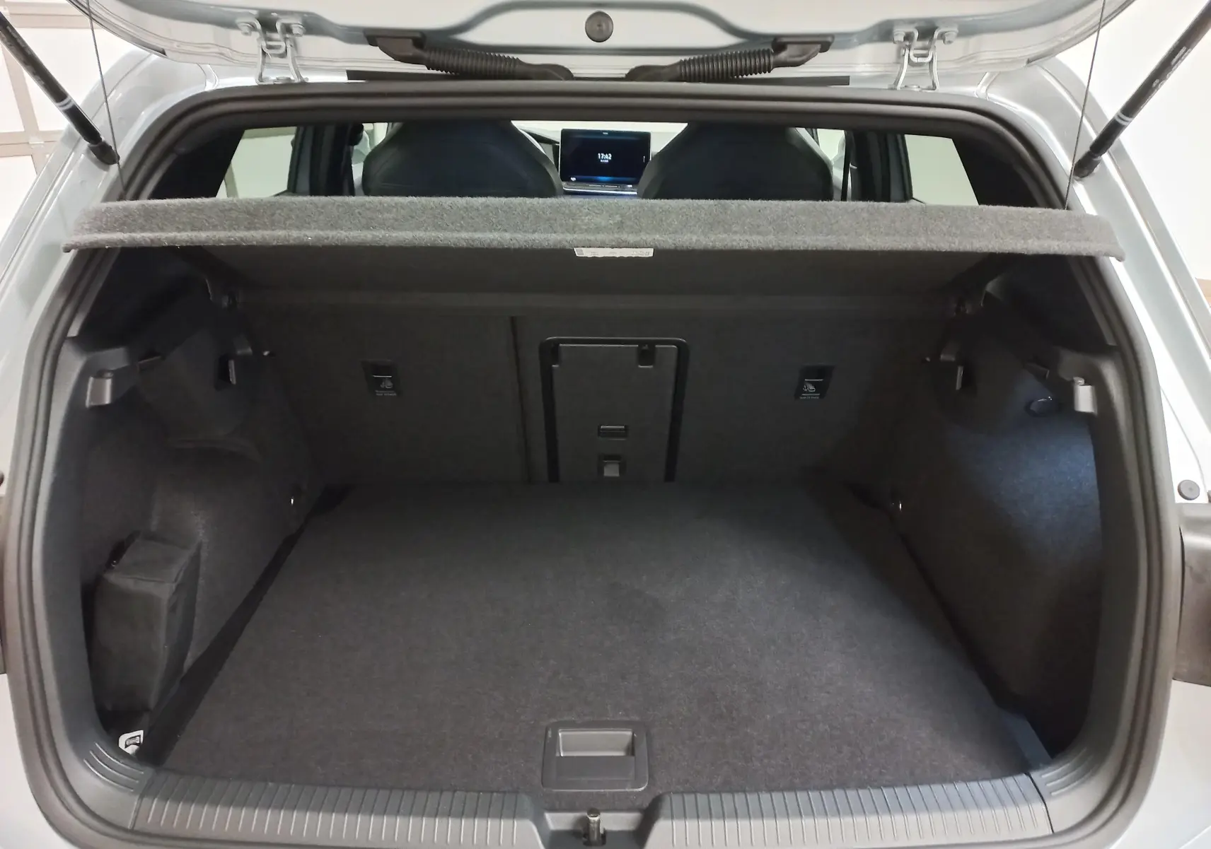 Vue arrière du coffre ouvert de la Volkswagen Golf 1.5 eTSI argent dolomite, montrant l'espace de chargement et la tablette cache-bagages.