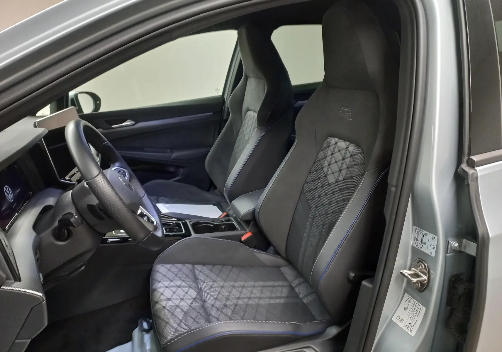 Intérieur avant droit de la Volkswagen Golf 1.5 eTSI R-Line argent Dolomite avec sièges sport et détails bleus.