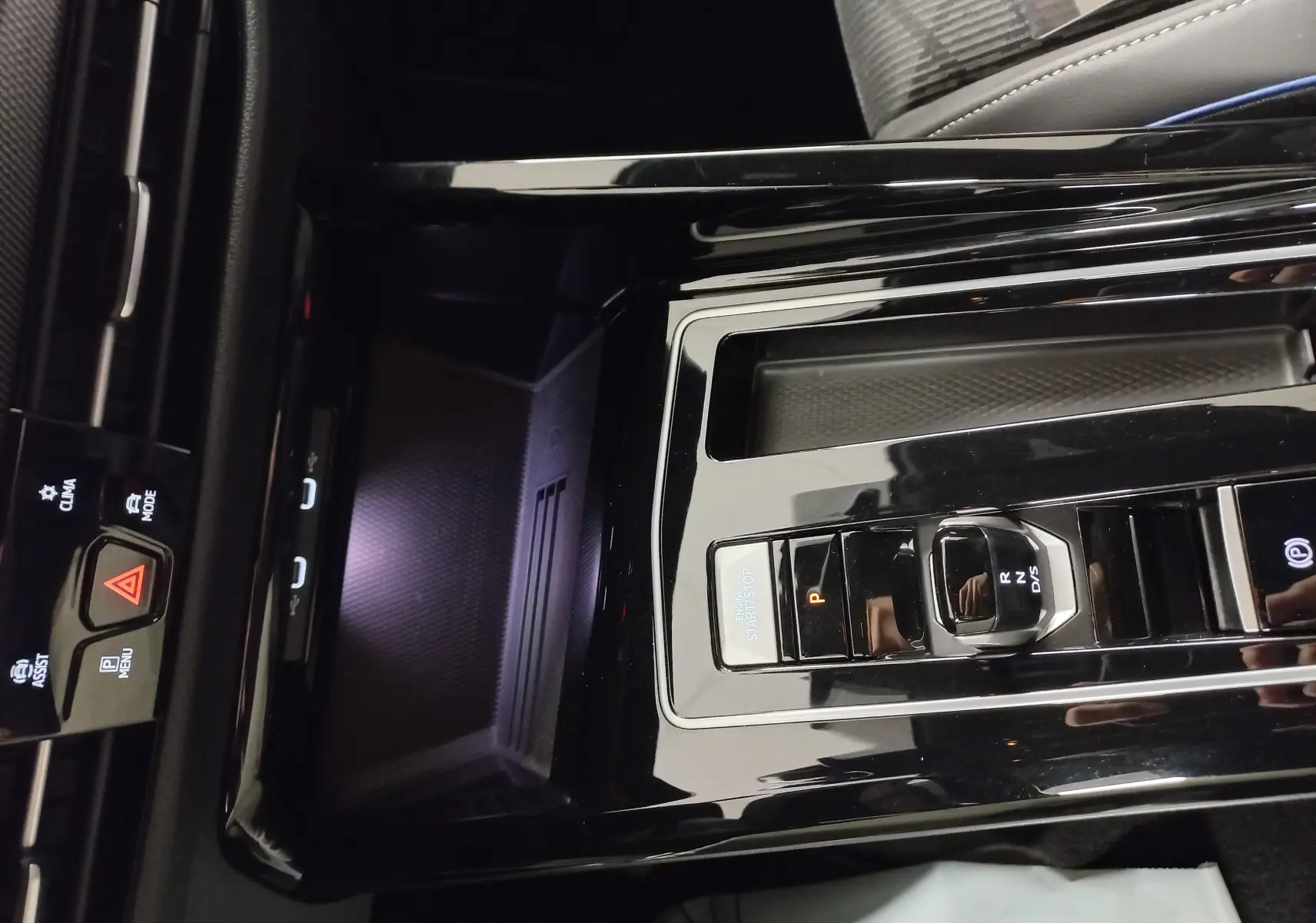 Vue rapprochée de la console centrale noire brillante de la Volkswagen Golf 1.5 eTSI R-Line avec sélecteur de boîte auto et bouton start/stop.