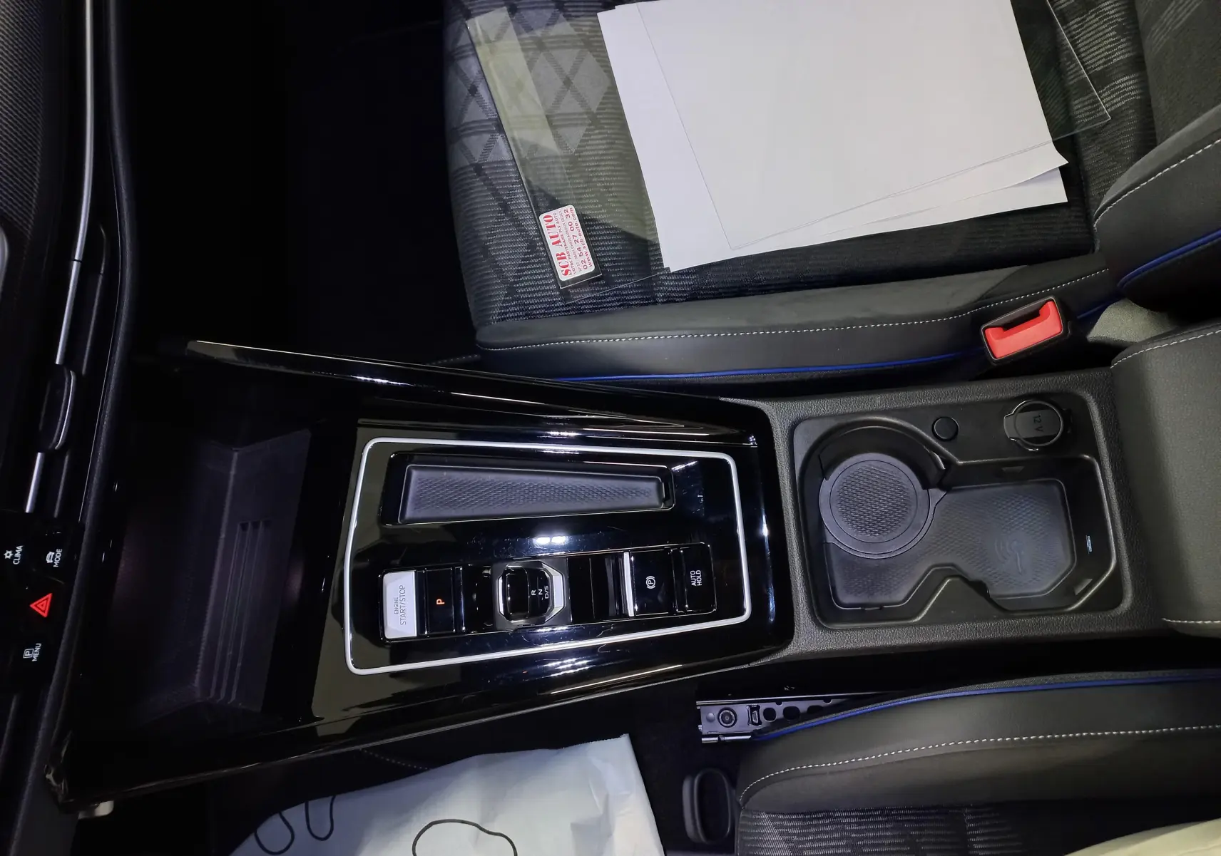 Vue plongeante sur la console centrale noire brillante de la Volkswagen Golf 1.5 eTSI R-Line avec sièges tissu gris et surpiqûres bleues.