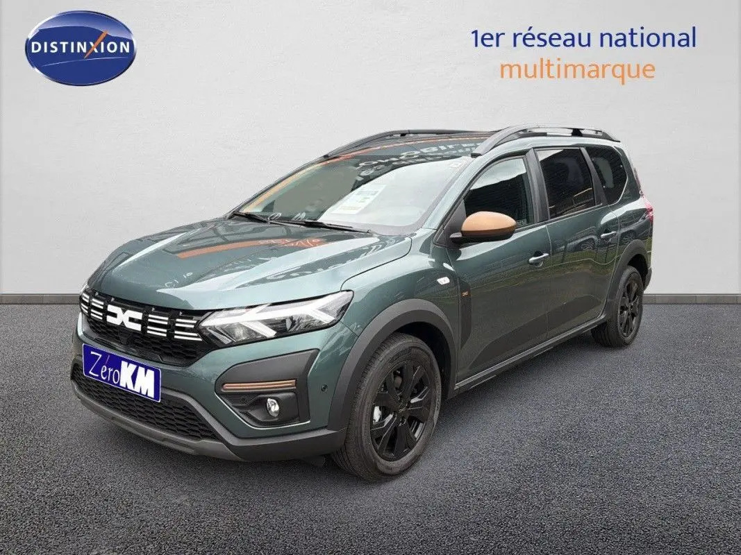 Vue 3/4 avant droite du Dacia Jogger 2026 vert cèdre métallisé avec rétroviseurs beige et jantes noires.