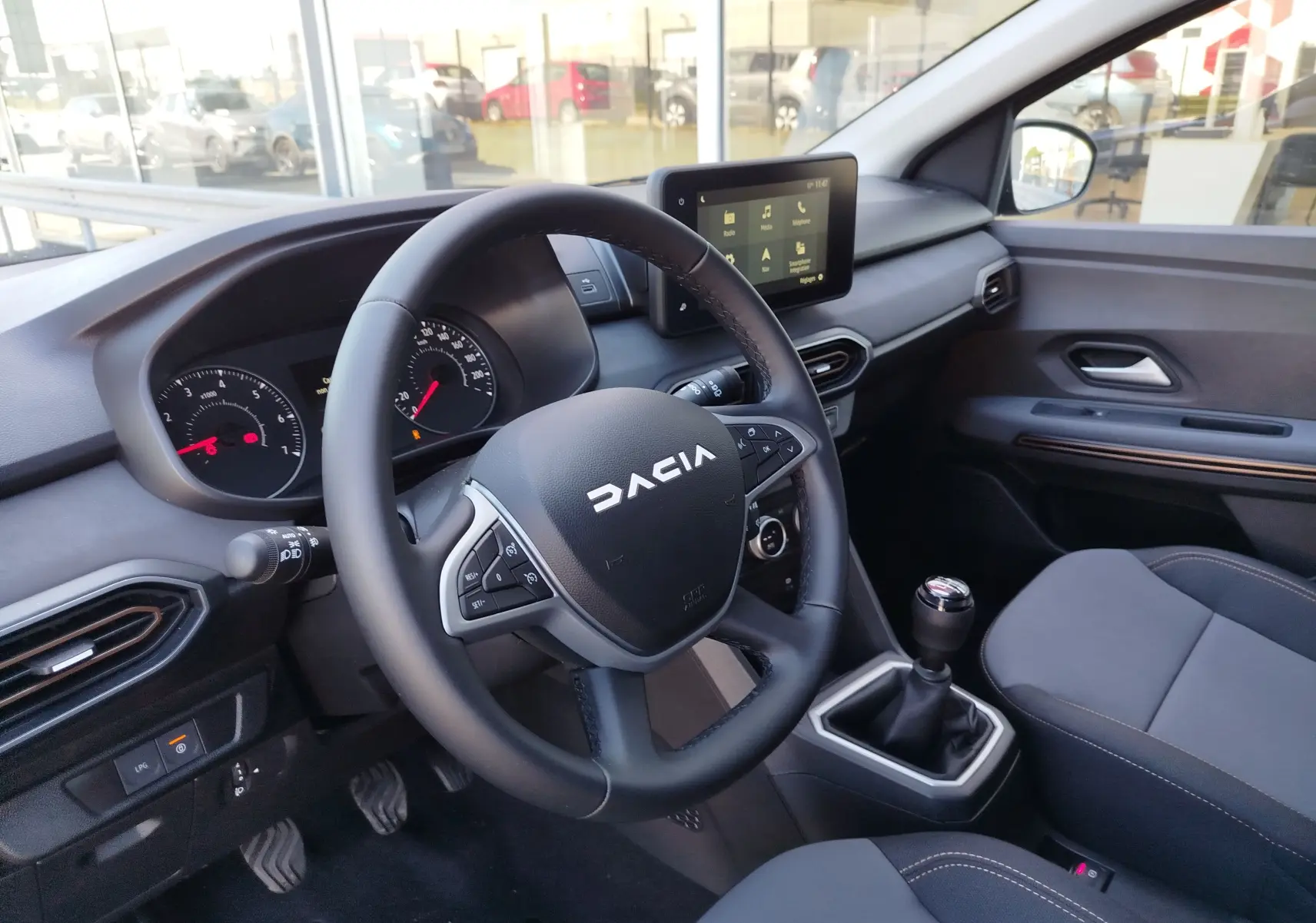 Vue intérieure côté conducteur du Dacia Jogger 2026, volant multifonction, écran tactile central et levier de vitesse manuel.