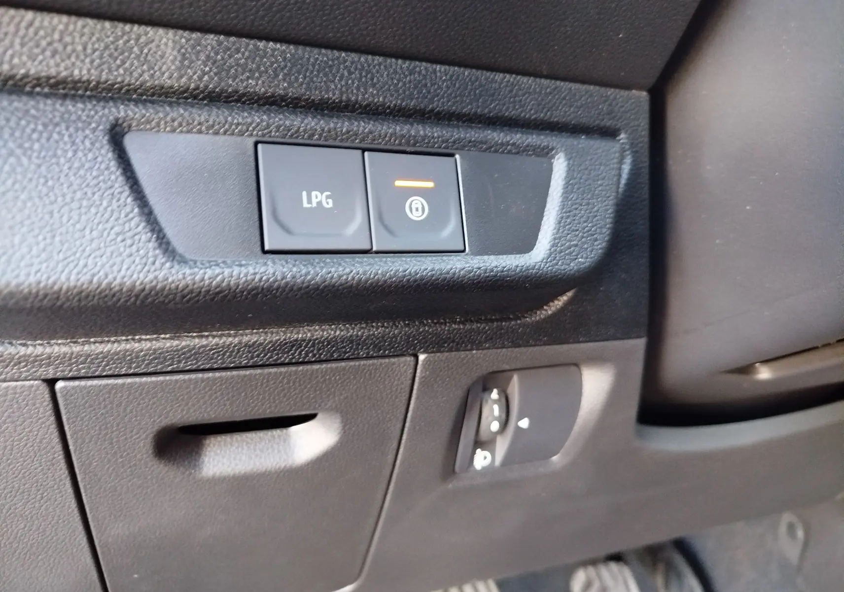 Détail intérieur côté gauche montrant les boutons de commande LPG et verrouillage du DACIA JOGGER vert cèdre métal.