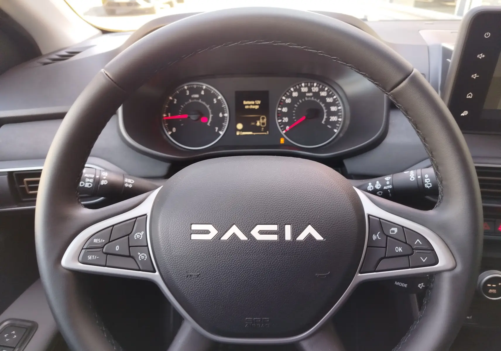 Vue rapprochée du volant noir de la Dacia Jogger 2026 avec commandes intégrées et tableau de bord numérique.