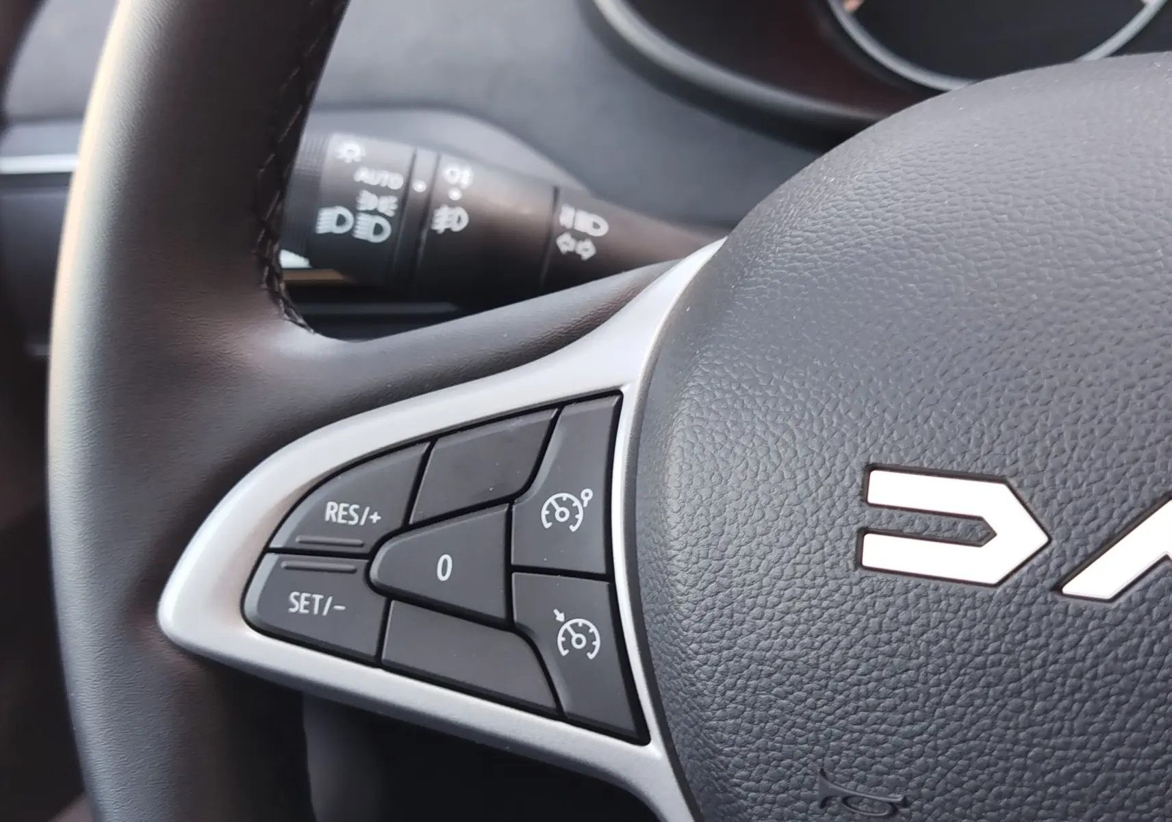 Gros plan sur les commandes de régulateur de vitesse au volant noir du Dacia Jogger 2026, intérieur sobre.