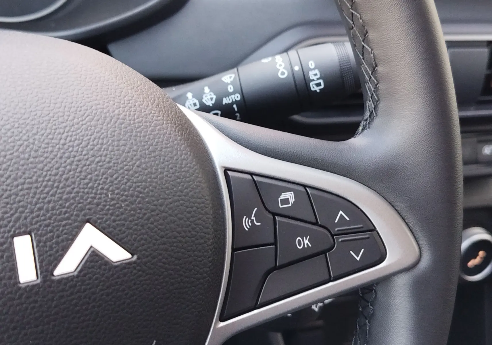 Gros plan sur le côté droit du volant noir du Dacia Jogger avec commandes multifonctions et surpiqûres visibles.