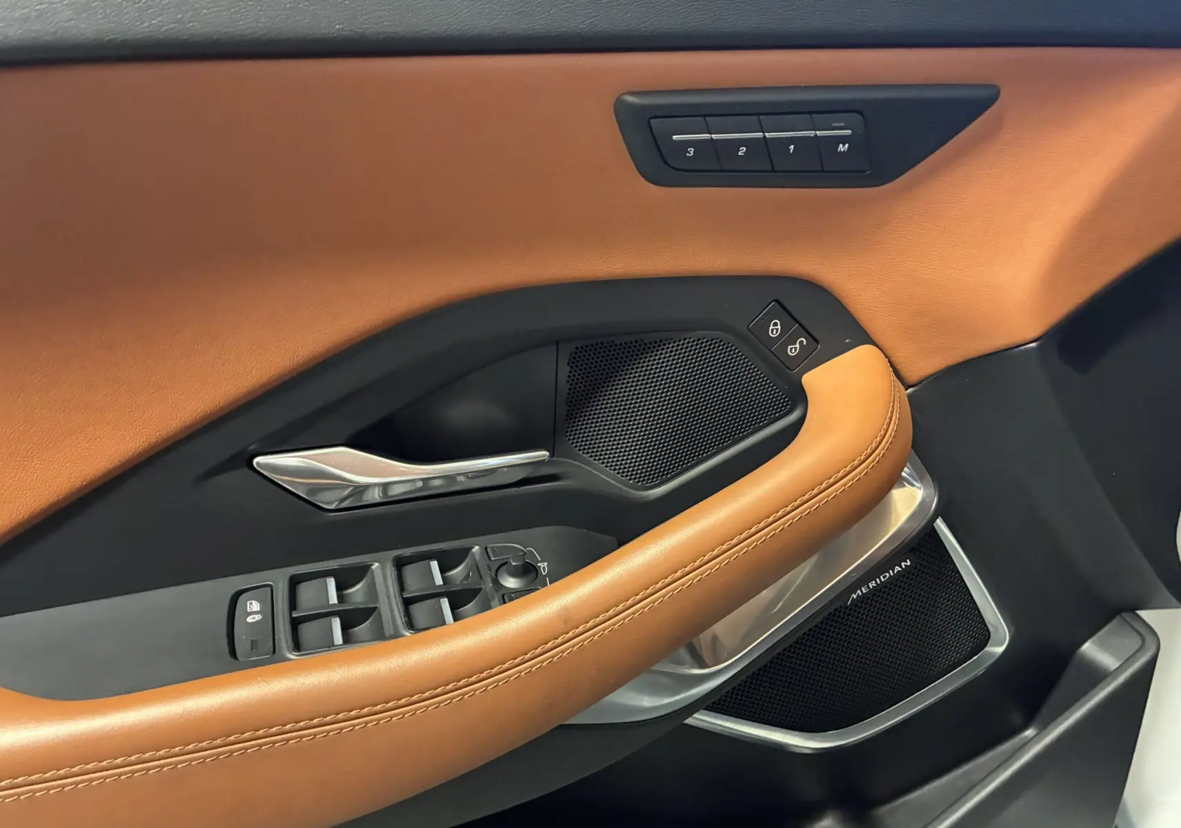 Détail de la porte côté conducteur du Jaguar E-PACE blanc 2019, avec garniture cuir brun et commandes électriques.
