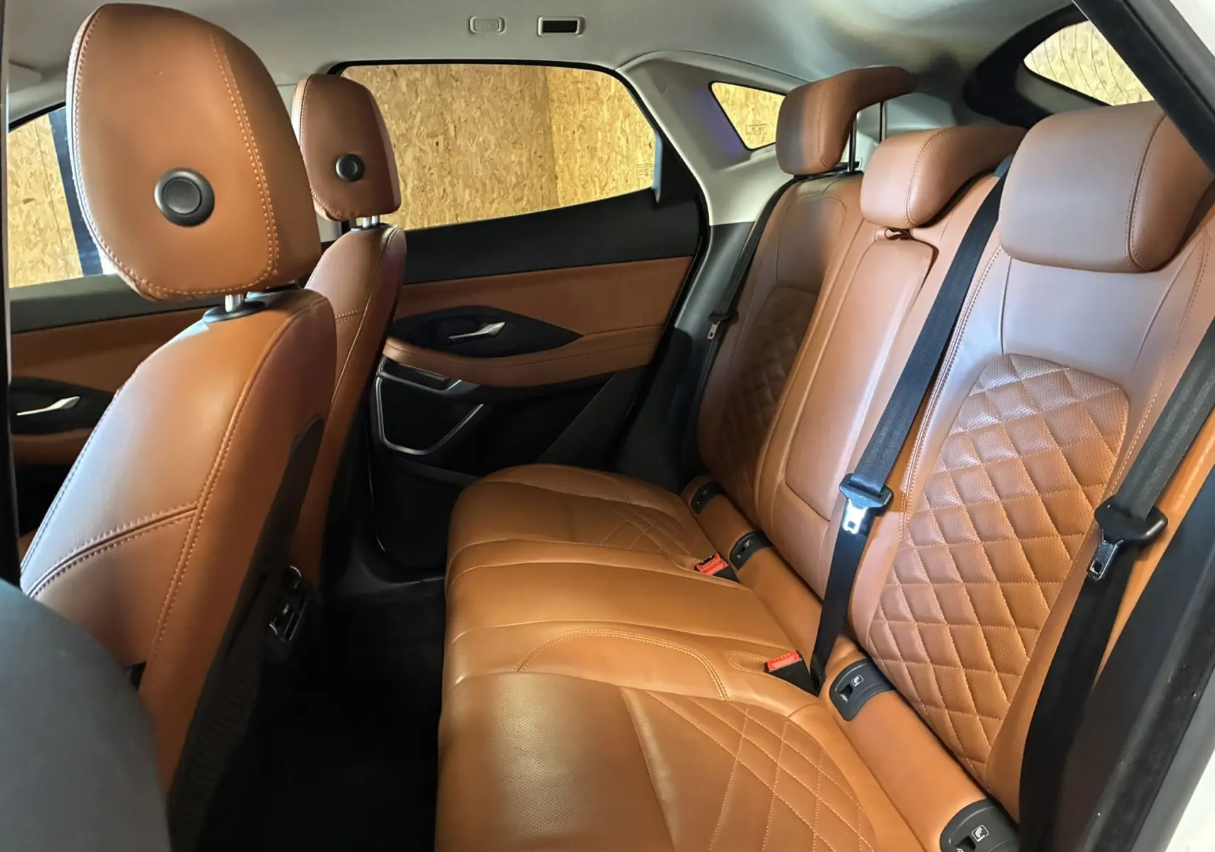 Vue intérieure arrière droite montrant les sièges en cuir brun matelassé du Jaguar E-PACE blanc de 2019.