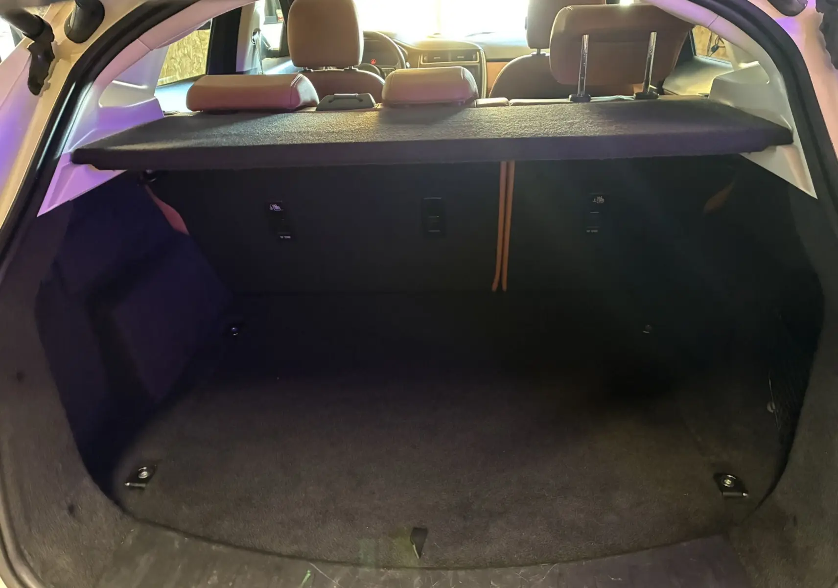 Coffre ouvert vu de l'arrière d'un Jaguar E-PACE blanc, montrant l'espace de chargement et la tablette cache-bagages.