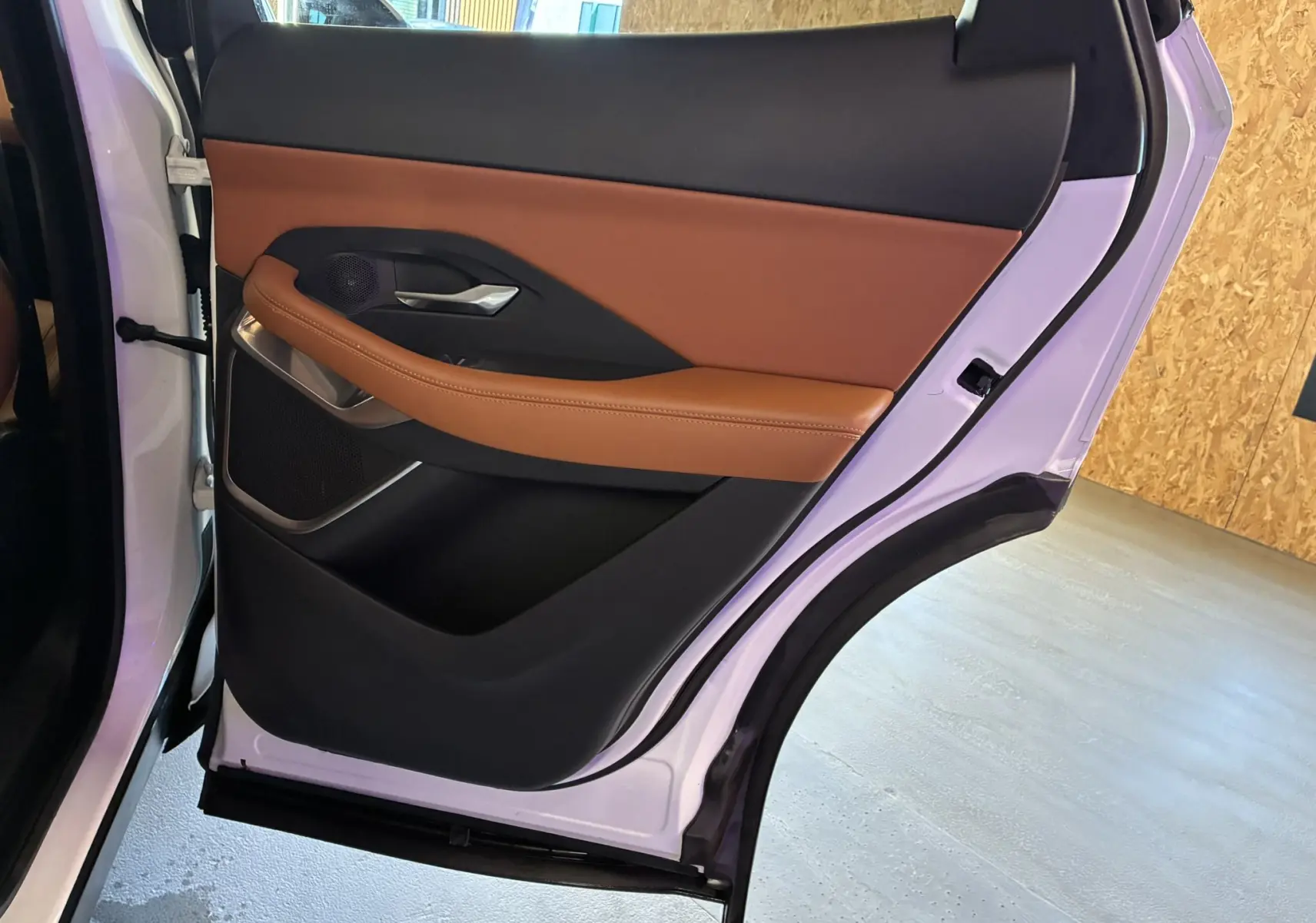 Vue rapprochée de la porte arrière droite blanche d’un Jaguar E-PACE 2019 avec garniture cuir brun et éléments noirs.