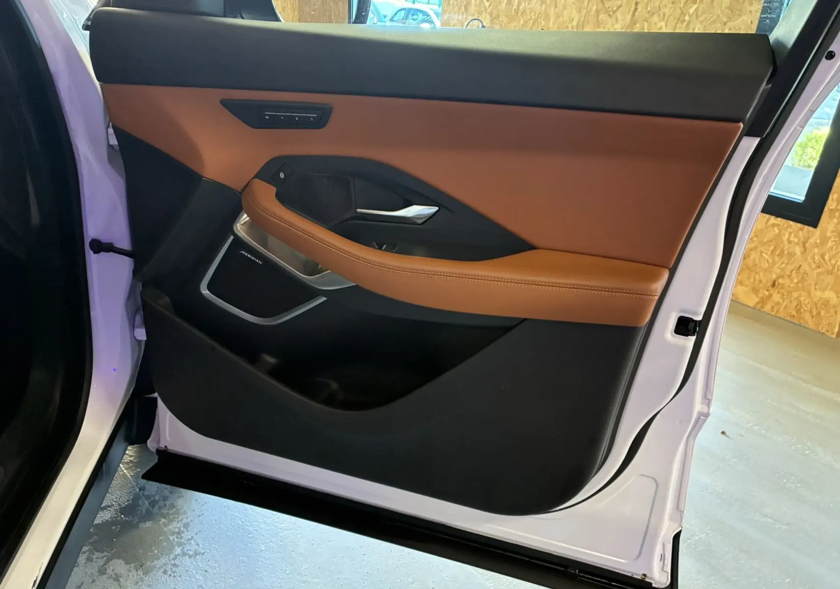 Vue intérieure de la porte arrière droite blanche du Jaguar E-PACE 2019 avec garniture cuir brun et détails noirs.