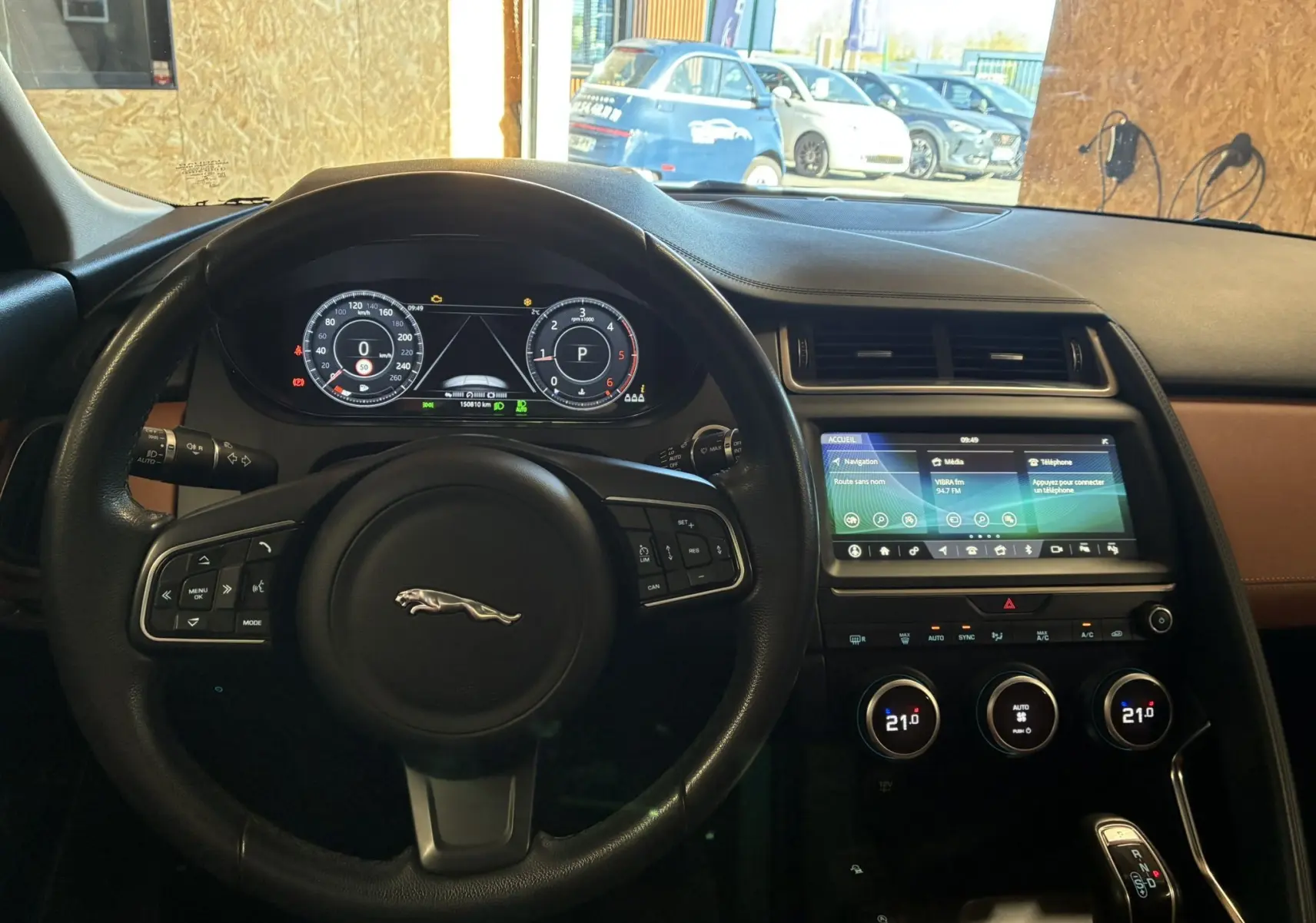 Vue intérieure du tableau de bord et volant noir du Jaguar E-PACE 2.0D 180 R-DYNAMIC HSE avec écran tactile et commandes digitales.