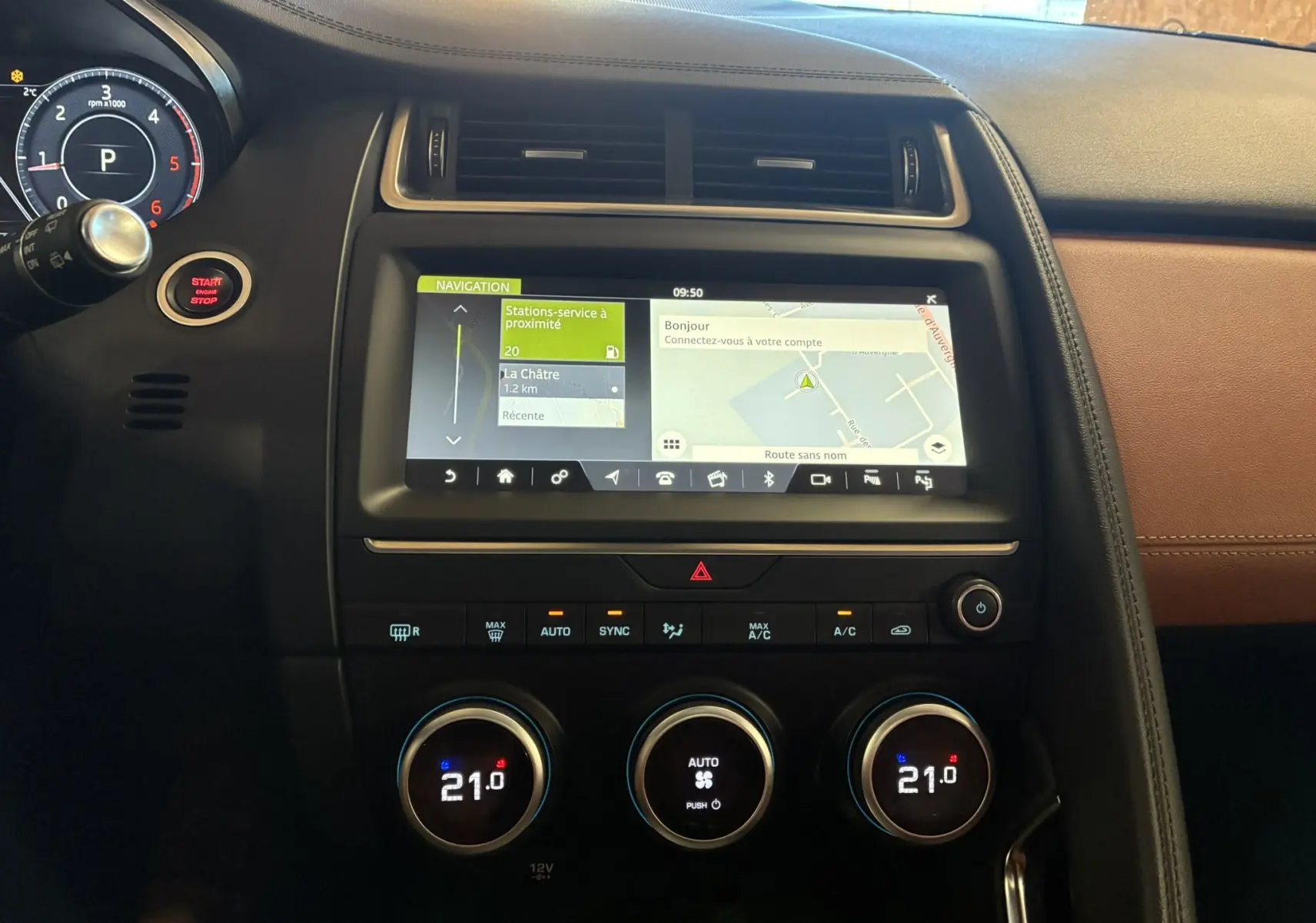 Vue intérieure centrée sur la console centrale du Jaguar E-PACE blanc, avec écran tactile de navigation et commandes climatisation.
