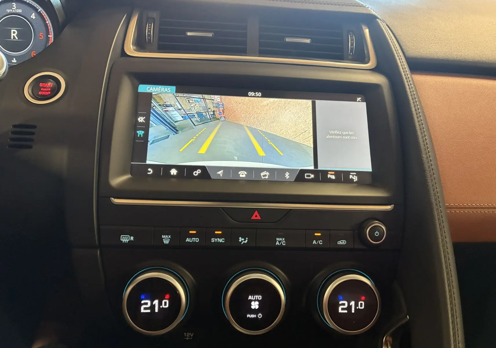 Vue intérieure du tableau de bord du Jaguar E-PACE 2019 avec écran de caméra de recul et commandes de climatisation à 21°C.