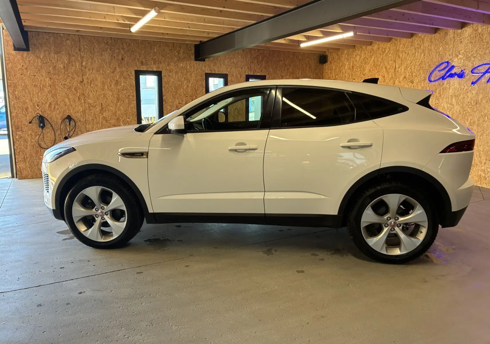 Jaguar E-PACE blanc vue de profil côté gauche, SUV compact avec jantes alliage et vitres teintées en intérieur.