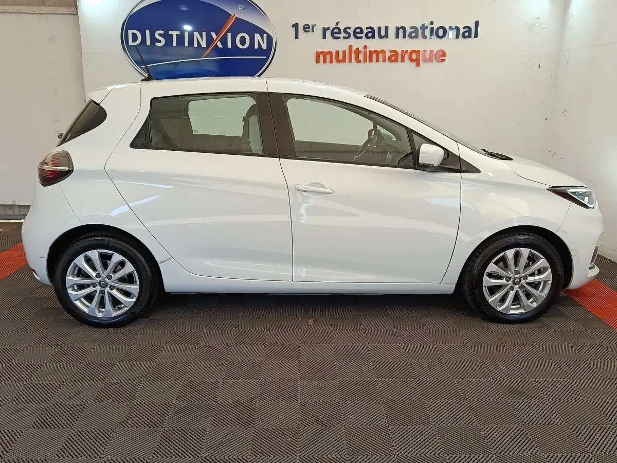 Profil latéral droit d'une Renault ZOE blanche 2021, compacte et électrique, avec jantes alliage et vitres teintées.