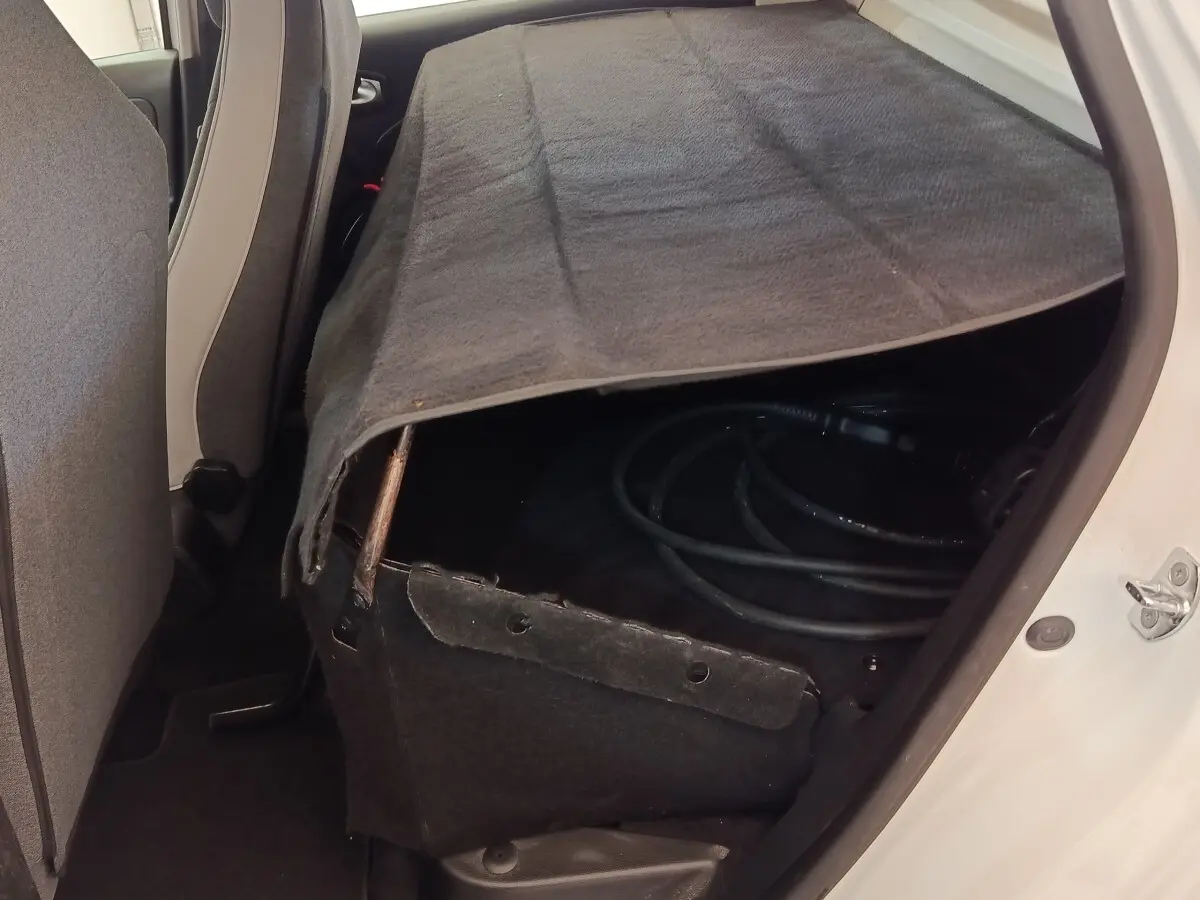 Vue intérieure arrière droite de la Renault ZOE blanche 2021, banquette rabattue avec câble de recharge visible sous une housse.