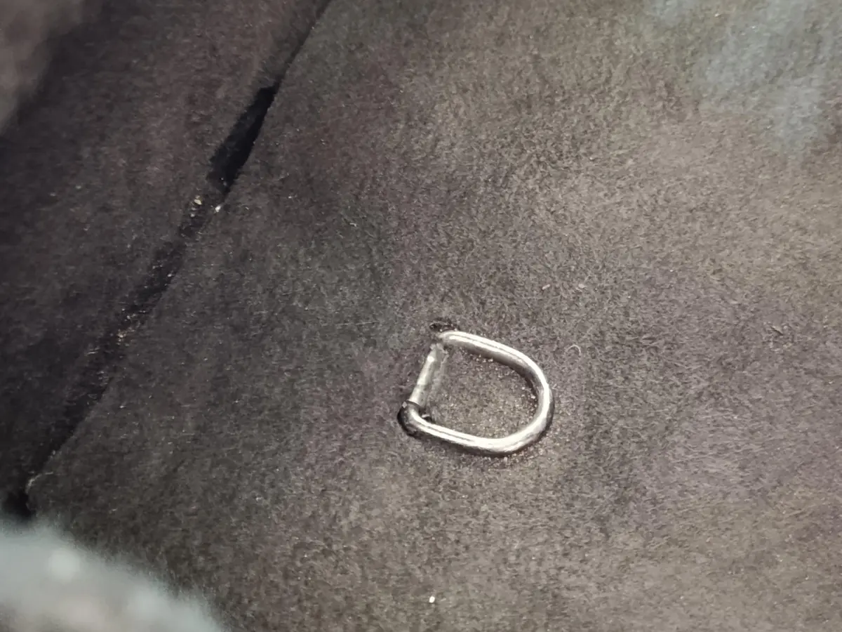 Détail d'un anneau d'attache métallique fixé sur la moquette noire du coffre d'une Renault ZOE blanche.