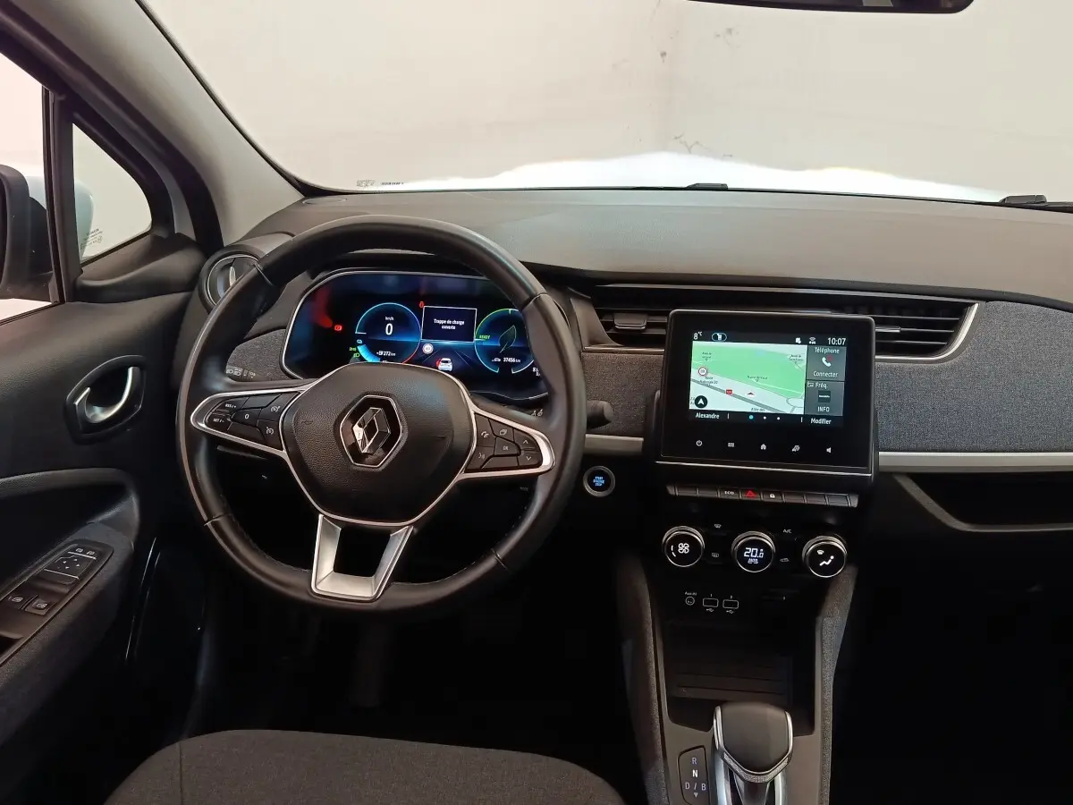 Vue intérieure avant de la Renault ZOE blanche 2021, volant cuir multifonctions et écran tactile central allumé.