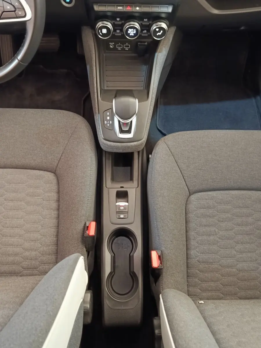 Vue plongeante sur la console centrale et les sièges gris du Renault ZOE Zen R135 blanc, avec levier de vitesses automatique.