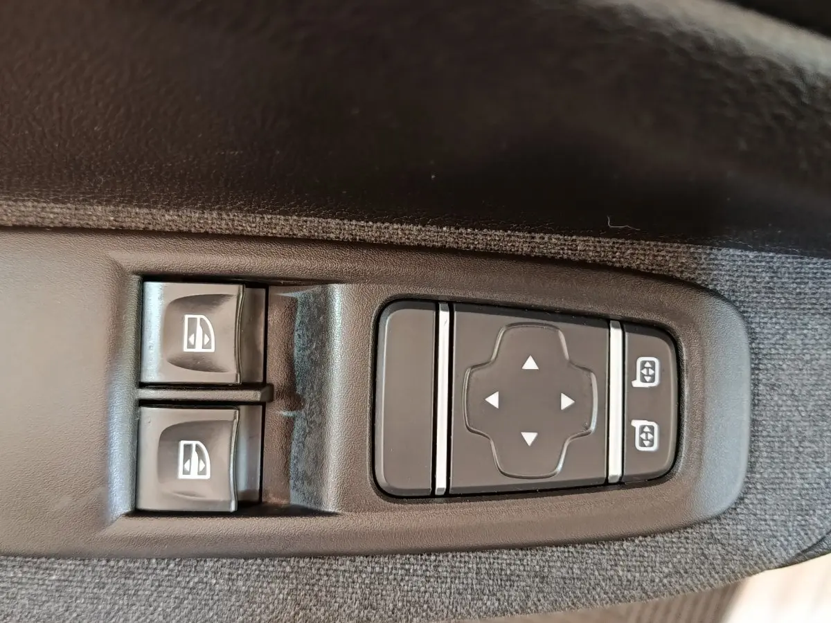 Gros plan sur les commandes de lève-vitres et réglage des rétroviseurs côté conducteur de la Renault ZOE blanche Zen R135 2021.