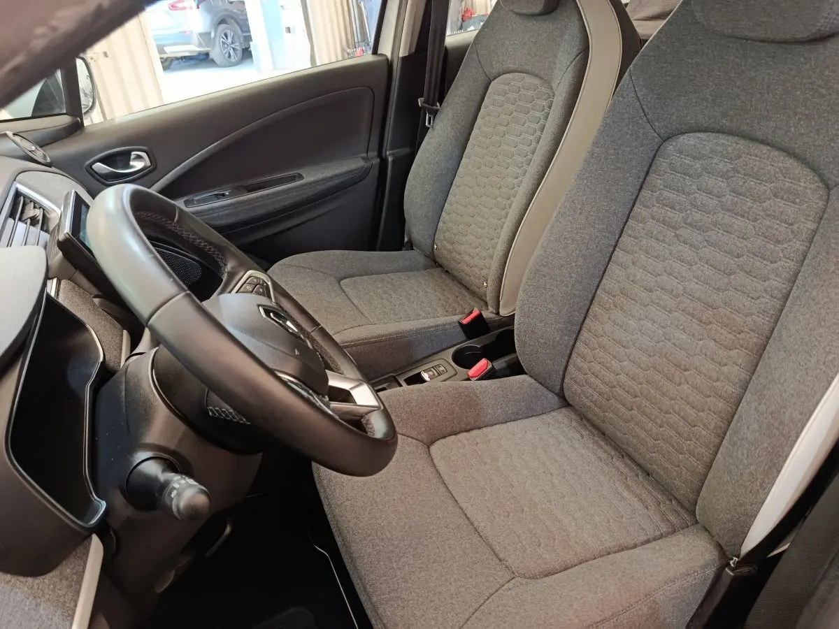 Vue intérieure côté conducteur de la Renault ZOE Zen 2021, volant cuir synthétique et sièges gris texturés.