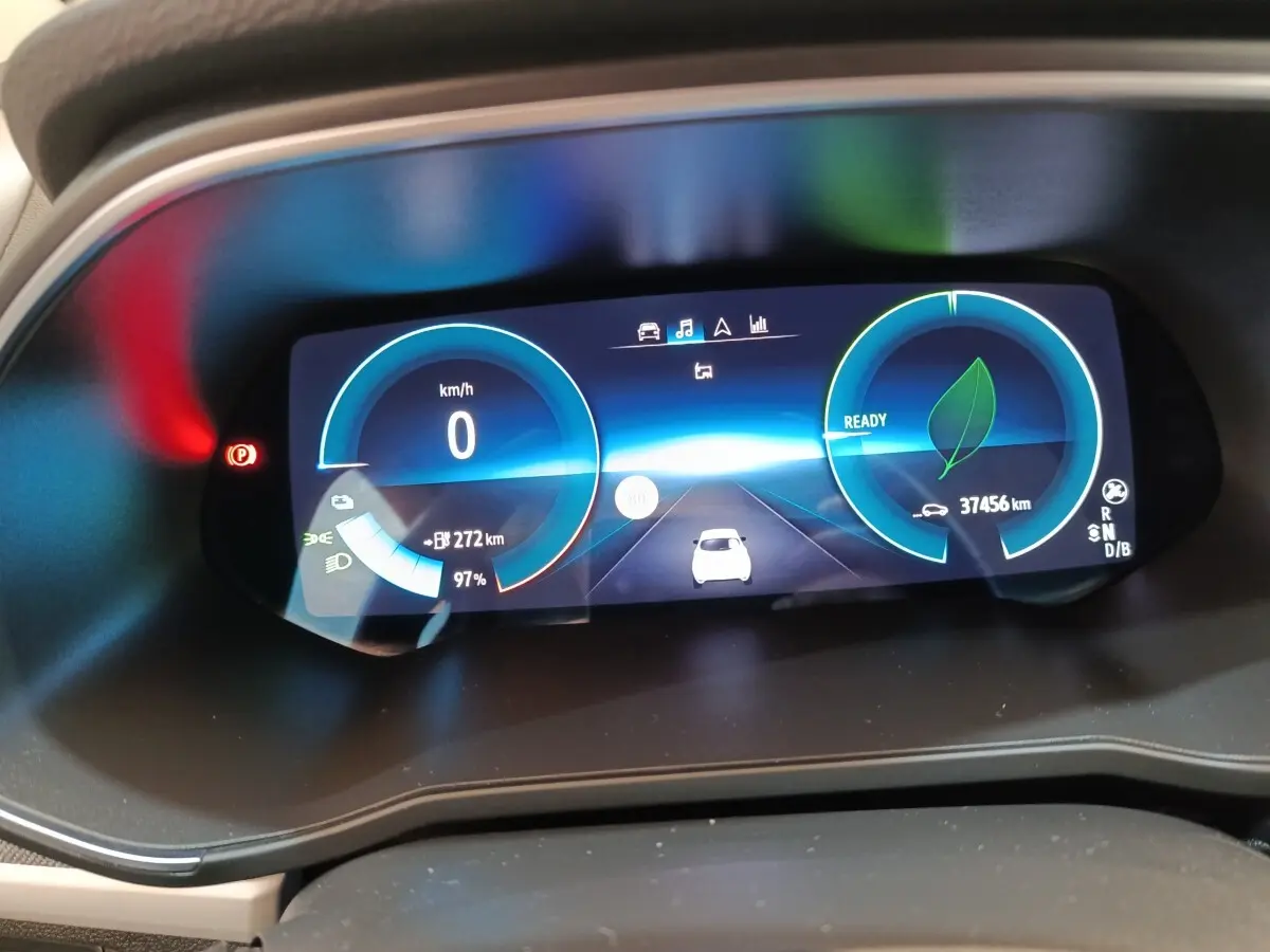 Gros plan sur le combiné d'instruments numérique de la Renault ZOE blanc, affichant vitesse, autonomie et état de charge.