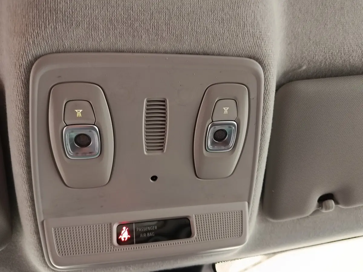 Vue intérieure du plafonnier gris clair avec éclairages et témoin airbag passager allumé dans une Renault ZOE blanche.