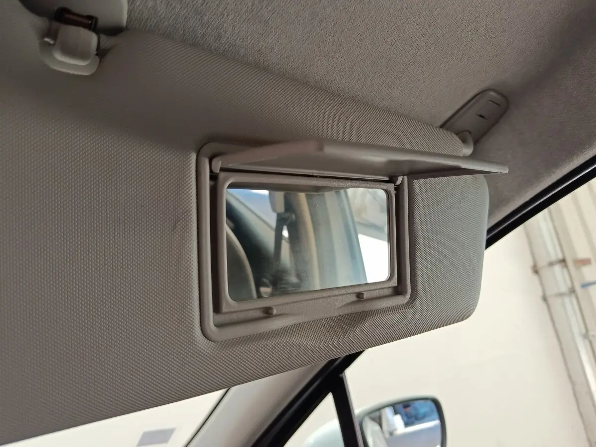 Miroir de courtoisie ouvert sur pare-soleil côté conducteur dans l'habitacle d'une Renault ZOE blanche 2021.