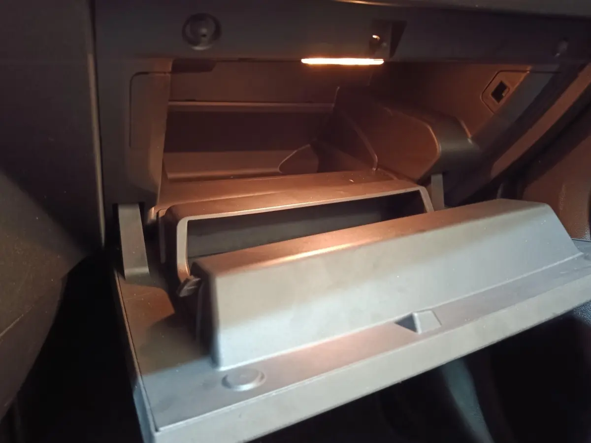 Gant de rangement ouvert éclairé dans l'habitacle sombre d'une Renault ZOE Zen R135 blanche de 2021.