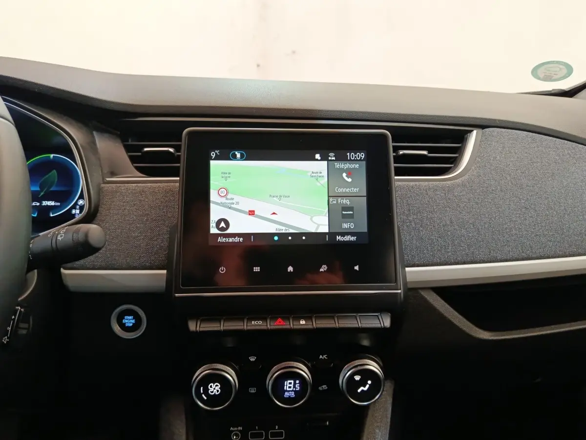 Tableau de bord central de Renault ZOE blanc, vue frontale sur l'écran tactile et commandes climatisation.