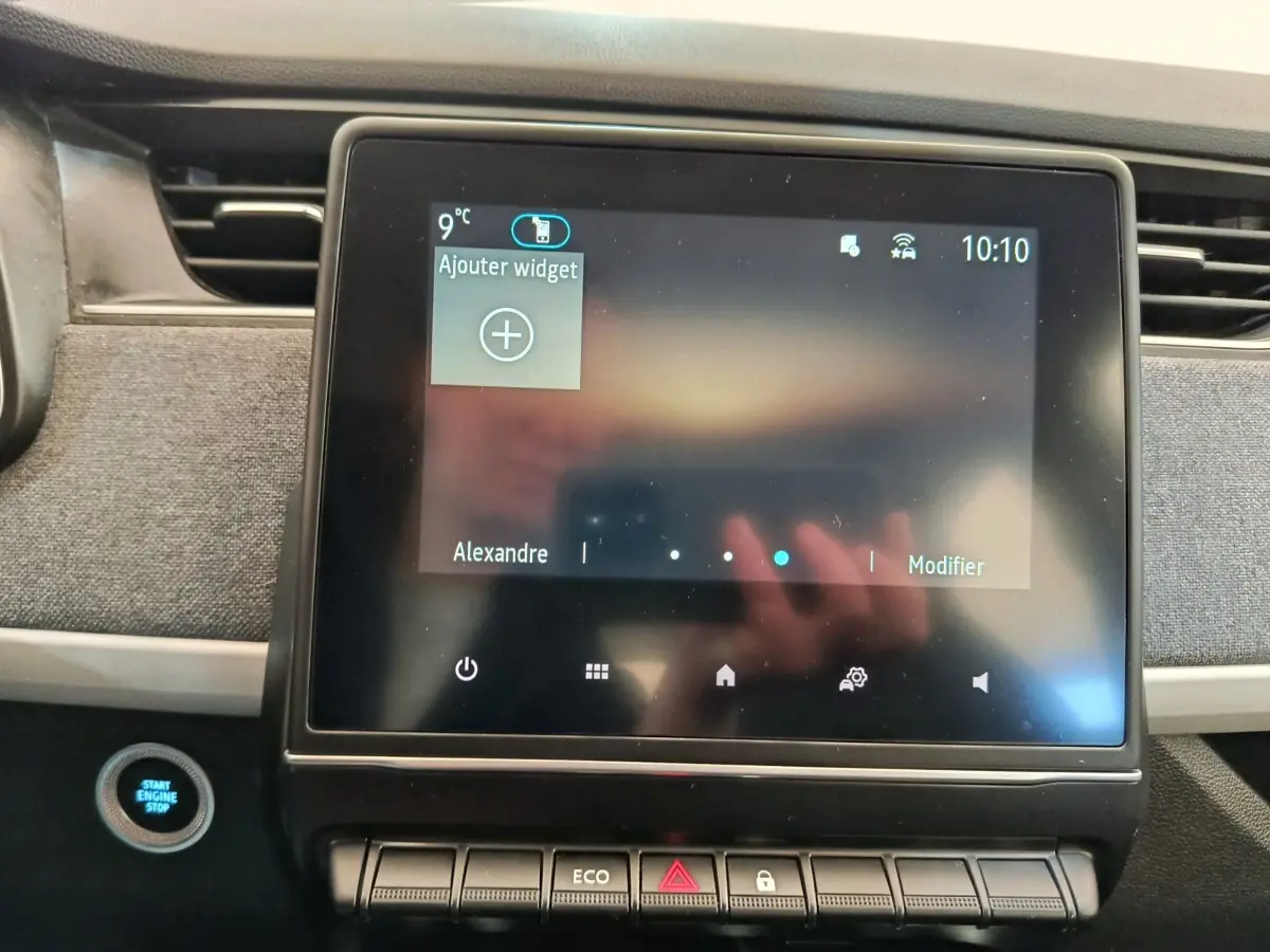 Écran tactile central allumé et bouton démarrage bleu dans l’habitacle de la Renault ZOE Zen blanche de 2021.